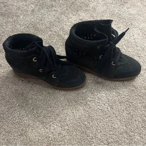 Svarta boots med snörning - Snygga svarta isabel marant skor i mocka med snörning och perforerade detaljer. De har en låg klack och rund tå, vilket ger en stilren look. Perfekta för höst och vår. Andvänds circa 16 gånger, i väldigt bra skick, skorna är i storlek 36 men passar mig som har 37💗 är även öppen för byten 