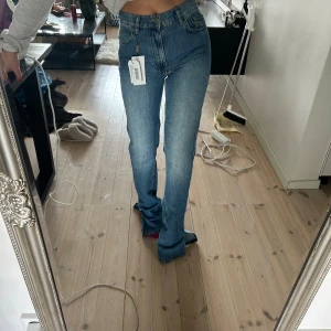 Blå jeans med slits från Nelly - Snygga helt nya blå jeans från Nelly med en midwaist passform och slitsdetaljer. Säljer då de är alldeles för lång för mig. Jag är 160cm lång. 