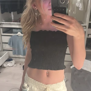 Svart tubtopp från Gina Tricot - Säljer en stilren svart tubtopp från Gina Tricot i storlek S. Toppen har en smockad design som ger en bekväm och flexibel passform. Perfekt för varma dagar eller som ett lager under en jacka.