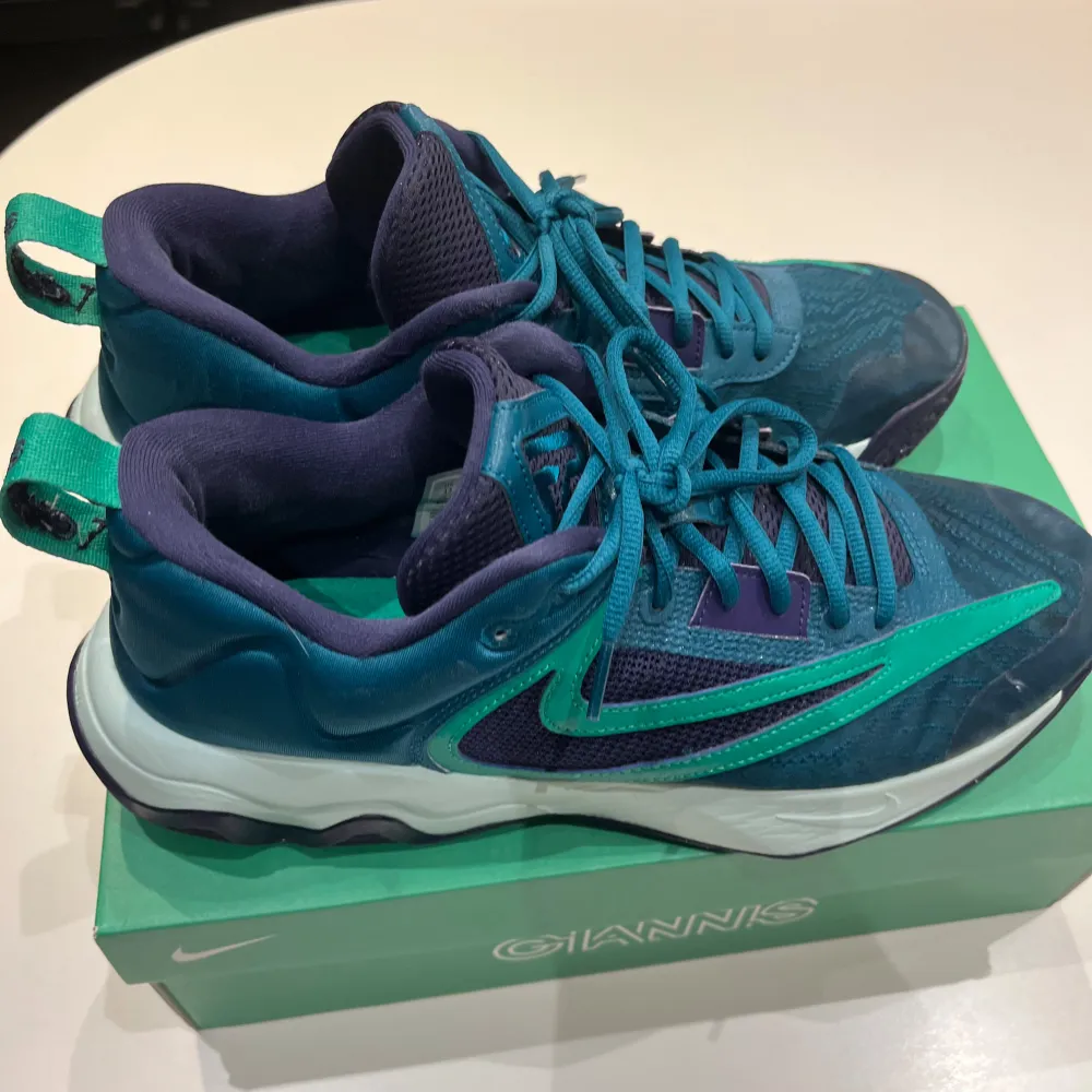 Snygga Nike Giannis Immortality 3 sneakers i en cool kombination av blå och grön. Skorna har en modern design med snörning och en bekväm sula. Perfekta för både sport och vardag.. Kengät.