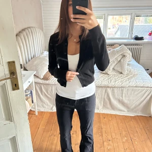 Svart kofta - Säljer en stilren svart kofta med knappar framtill. Perfekt att bära över en topp för en avslappnad look. Koftan har långa ärmar och en klassisk design.