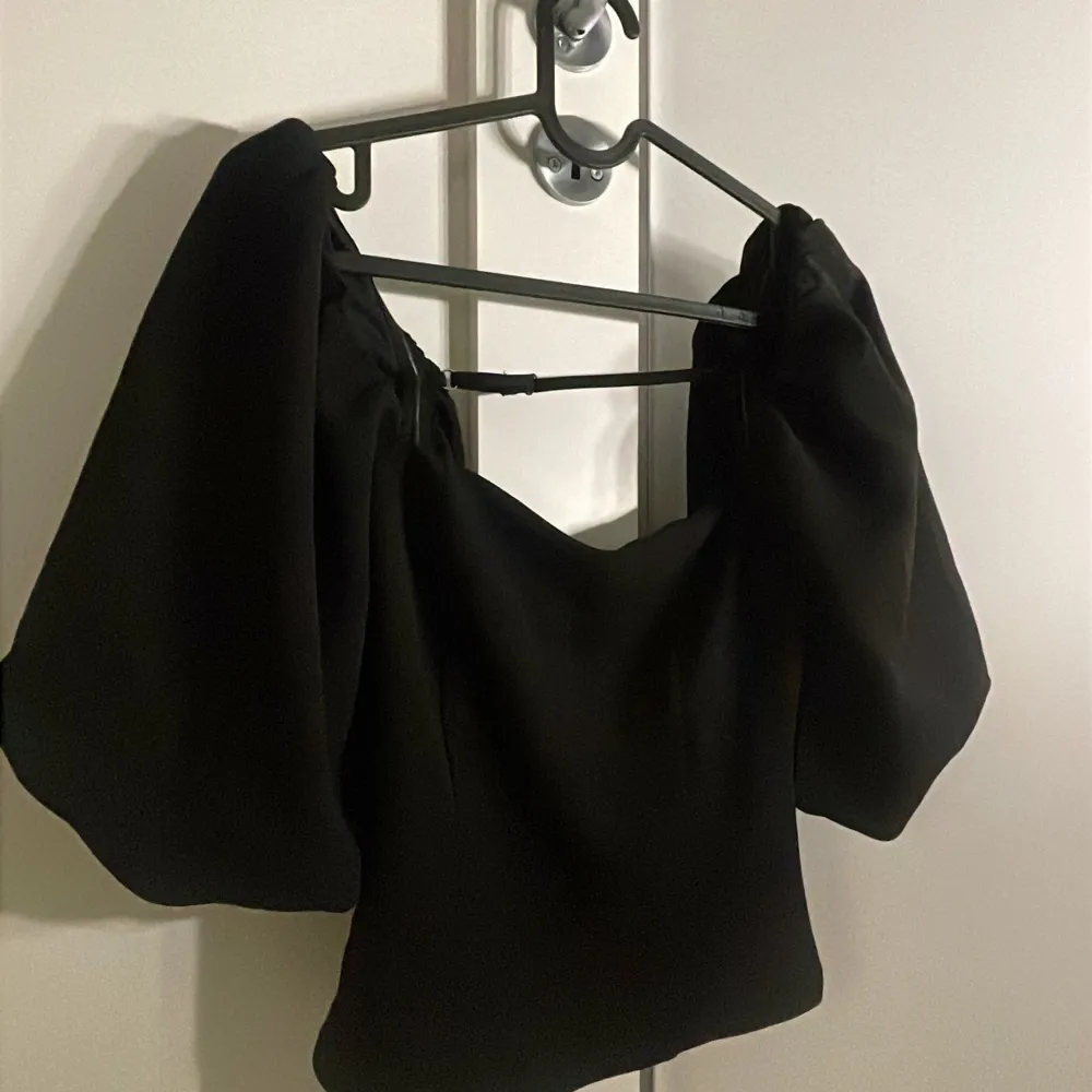 Snygg svart offshoulder topp med puffiga ärmar. Perfekt för en stilren look. Toppen har en elegant design som framhäver axlarna. Aldrig använt . Yläosat.