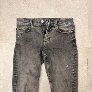 Grå jeans med slitningar - Schyssta grå jeans med slitningar från Zara. Skick 8/10 Jeansen är endast använda ett fåtal gånger | Model: Slim fit | Storlek: 164 (passar w27 l30) | Det är bara att skriva om ni har frågor eller funderingar!