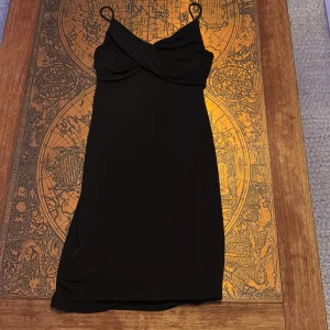 Svart klänning från Vero Moda - Elegant svart klänning från Vero Moda med smala axelband och en stilren design. Den är medellång i längden och har ett väldigt skönt material 