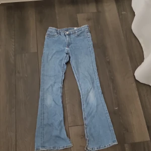 Blå bootcut jeans - Snygga blå bootcut jeans med dragkedja och knapp framtill. Klassisk femficksdesign och lätt utsvängda ben. Perfekta för en avslappnad stil.