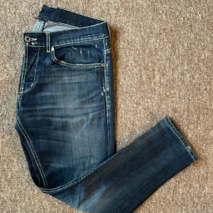 Dondup jeans  - Snygga mörkblå jeans med en klassisk femficksdesign och slitna detaljer. Byxorna har en knappgylf och är perfekta för en avslappnad stil. De har en rak passform och är tillverkade i ett robust denimtyg. Storleken är 34 men är uppsydda så sitter som 30 i längd. Är 180 och sitter helt perfekt på mig!!