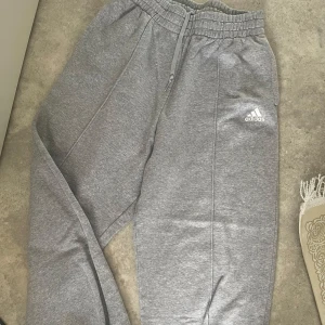 oversized grå mjukisbyxor från adidas - säljer ett par oversized grå mjukisbyxor från Adidas i storlek S. de är superbekväma med elastisk midja och muddar vid benen. knappt använda!!