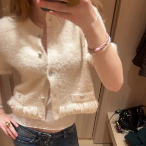 Vit kortärmad kofta med pärldetaljer från H&M - Säljer min söta vita kortärmade kofta från H&M som aldrig är använd. Säljer då den inte kommer till användning. Koftan är i storlek L men passar mig lite oversized som är storlek S. 