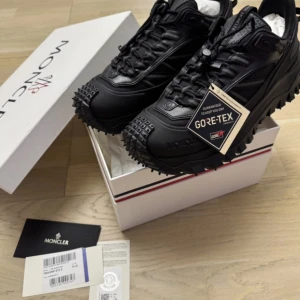 Moncler GTX Trailgrip  - Moncler skor av högsta kvalitet. Hela skon är Gore-Tex och vibram sulan är helt perfekt mot halka eller vilken utomhusaktivitet som helst. Greppet på dessa är 10/10 men skorna är fortfarande otroligt lätta tack vare kolfiberchassit i sulan. Helt nya med tag kvar. Givetvis äkta 