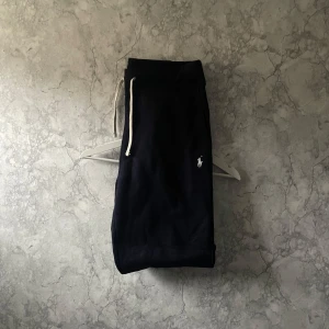 Mörkblåa mjukisbyxor från Polo Ralph Lauren - Säljer ett par mörkblåa mjukisbyxor från Polo Ralph Lauren med en liten broderad logga på benet.🏇Byxorna har snörning i midjan för justerbar passform. Perfekta för en avslappnad stil.🦋