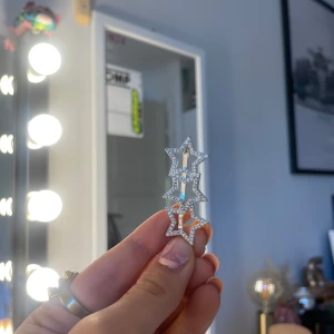 Glittrigt stjärnformat hårspänne - Snyggt hårspänne i form av tre sammanlänkade stjärnor med glittriga detaljer. Perfekt för att ge en extra touch till din outfit. Den är i en elegant silverfärg och passar bra till festliga tillfällen.