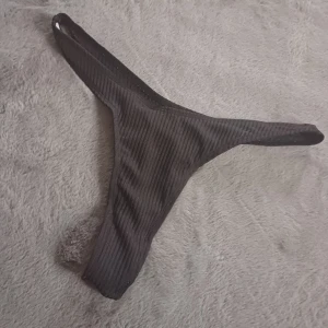 Svart ribbad bikiniunderdel - Snygg svart ribbad bikiniunderdel med en stilren design. Perfekt för en dag på stranden eller vid poolen. Den har en enkel och modern look som passar till många olika överdelar.