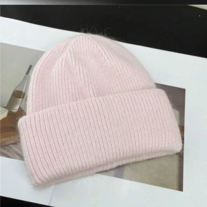 Rosa stickad mössa - Söt och stilren rosa stickad mössa med ribbad design. Perfekt för att hålla värmen under kyliga dagar. Passar bra till både vardag och mer avslappnade tillfällen.