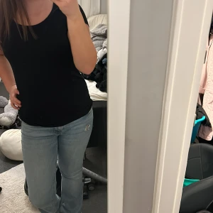 Svart kortärmad topp - Säljer en stilren svart kortärmad topp. Perfekt för en enkel och klassisk look. Toppen har en tight passform som framhäver figuren.