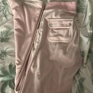 Rosa mjukisbyxor från Juicy Couture - Säljer ett par rosa mjukisbyxor från Juicy Couture. Byxorna har små defekter , knappen är tappad på höger ficka och bandet har nagellim . Dom är lite smutsiga vid änden av byxan annars perfekt.