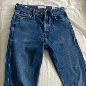 Blå jeans från Jack & Jones - Snygga blå jeans från Jack & Jones med klassisk femficksdesign och knappgylf. Perfekta för en avslappnad stil. Tillverkade i bomull för en bekväm passform.