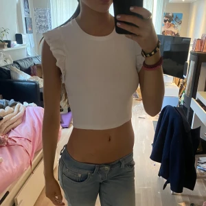 Vit ribbad croppad topp - Säljer en vit ribbad croppad topp med volangdetaljer på axlarna från zara.  Perfekt till sommaren!! 😍😍