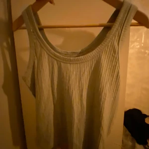 Grön ribbad linnetopp - Snygg grön ribbad linnetopp med breda axelband och rund halsringning. Perfekt för en stilren och enkel look. Passar bra till både jeans och kjol.