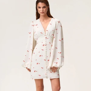 Vit blommig Adooreklänning!  - Superfin vit kortklänning med små röda blommor från adoore! Passar perfekt till midsommar! Använd ca 2 gånger. Det är en knapp isydd i ryggen. Knappen går att sprättas bort lätt så att dragkedjan kan användas. Inget som är borta på klänningen! 