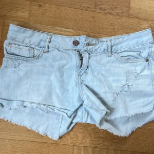 Ljusblå jeansshorts - Ljusblå jeansshorts med råa fransade kanter och slitna detaljer framtill. Klassisk femficksmodell med knapp och dragkedja. Jag som vanligtvis har 36 (s) tycker jag är lite stora för mig, oklart vart dessa är ifrån!🥰