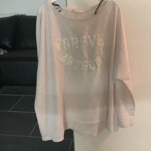 Ljusrosa oversized tröja med text - Ljusrosa oversized tröja med glittrig text 'FOREVER AWESOME' framtill. Tröjan har rund halsringning och långa ärmar. Perfekt för en avslappnad och trendig look.