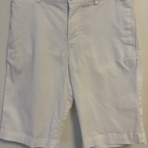 Vita shorts från Polo Ralph Lauren - Klassiska vita shorts från Polo Ralph Lauren med normal passform. Shortsen har bälteshällor, knappgylf och två bakfickor med knappar. Perfekta för varma dagar och stilrena outfits. De är i storlek 16 så passar 15-17 åringar ungefär😊