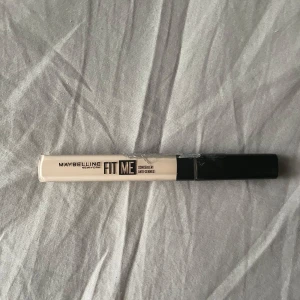 Maybelline Fit Me Concealer - Maybelline Fit Me Concealer i en ljus beige nyans. Kommer i en smal, genomskinlig tub med svart lock och applikator. Perfekt för att täcka ojämnheter och mörka ringar under ögonen. Innehåller 6,8 ml.
