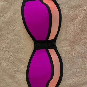 Bikini topp - Trendig bikinitop i snygg lila och ljusrosa färg. Pads i och dragkedja fram. Knäppe där bak. Sitter tajt runt om och håller sig uppe. Passar tyvärr inte mig längre, köpte för något år sedan men endast använd under en sommar☀️🩷💜