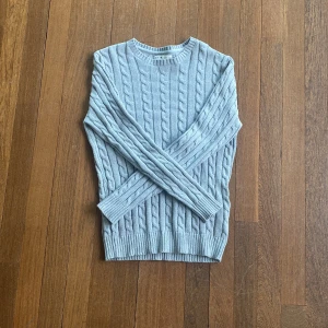 Ljusgrå kabelstickad tröja från S.C.W. - Säljer en ljusgrå kabelstickad tröja från S.C.W. i storlek M. Tröjan har rund halsringning, lång ärm och klassiskt flätmönster. Perfekt för lager-på-lager och passar till många olika stilar.