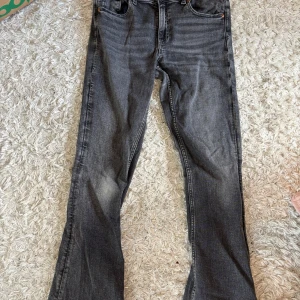 Grå bootcut jeans från Gina Tricot - Säljer ett par grå jeans från Gina Tricot i bootcut-modell. Jeansen har klassisk femficksdesign och normal passform. Perfekta för dig som gillar en tidlös stil med lite utsvängda ben. jeansen är ihopsydda mellan benen men tycker inte det är något man lägger märke till😇