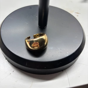 Bred guldig ring - Säljer en bred och stilren ring i guldton. Ringen är öppen baktill vilket gör den justerbar i storlek. Perfekt för dig som gillar minimalistiska och trendiga accessoarer.