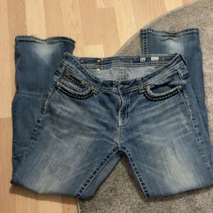 Miss me byxor bootcut - Säljer ett par blå jeansbyxor med snygga broderade detaljer på bakfickorna och kontrastsömmar. Byxorna har bootcut-modell och klassisk femficksdesign. Perfekta för dig som gillar en lite mer unik jeansstil.