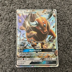 Tauros GX - Tauros GX är ett kraftfullt Pokémonkort med 180 HP och flera attacker, inklusive Rage och Mad Bull GX. Perfekt för samlare och Pokémon-fans som vill stärka sin kortlek med en glänsande och sällsynt GX-kort.