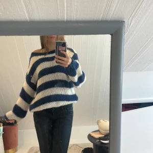 Randig stickad tröja från Design by si  - Säljer en mysig stickad tröja från Design by si med breda blå och vita ränder. Tröjan har en oversized passform, långa ärmar och är perfekt för kyligare dagar. Superfin att styla med jeans eller kjol!