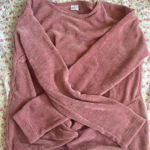 Rosa ribbad tröja från Lindex - Mysig rosa ribbad tröja från Lindex i storlek 146/152. Tröjan har lång ärm och är tillverkad i ett mjukt material som passar perfekt för kyligare dagar. Enkel och stilren design som är lätt att matcha med olika outfits. Har som en liten Knut längst ner av tröjan 