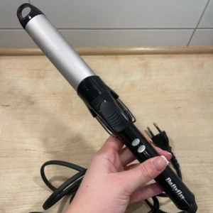 locktång från BaByliss - Säljer en svart och silver locktång från BaByliss med sladd och EU-kontakt. Tången har en rundad cylinder i metall och ett handtag i svart plast med vita knappar. Perfekt för att skapa snygga lockar och vågor. Använd en gång. Tryck på KÖP NU så postar jag så snabbt som möjligt!! 🩷🩷