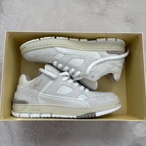 Vita sneakers från Axel Arigato - Ett par helt nya oanvända snygga vita sneakers från Axel Arigato med detaljer i mocka och skinn. Skorna har rund tå, platt sula och klassisk snörning. Perfekta för dig som gillar stilrena och trendiga sneakers med diskret branding på sidan.  Inköpspris 3500kr säljer nu för 2200kr