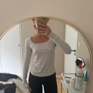 Vit ribbad långärmad topp - Säljer en vit ribbad långärmad topp med rundad halsringning. Sitter figurnära och är perfekt att styla till både jeans och kjol. Enkel och stilren design som passar till många olika outfits.