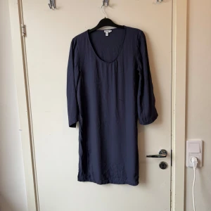 Mörkblå klänning från Filippa K - Enkel och stilren mörkblå klänning från Filippa K med rundad urringning och långa ärmar. Modellen är rak och slutar strax ovanför knäna. Tillverkad i mjukt och lätt material som ger en avslappnad känsla. Storlek XS. Fint skick, men något mer använd. 