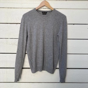 Grå kashmirtröja från Massimo Dutti - Säljer en stilren grå tröja i 100% kashmir från Massimo Dutti. Tröjan har rund halsringning och långa ärmar, perfekt för lager-på-lager eller som den är. Supermjuk och klassisk modell. Väldigt skön och funkar bra på sommaren.