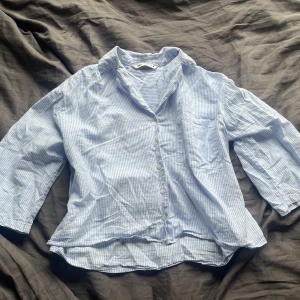 Randig skjorta från Zara  - Säljer en ljusblå och vit randig skjorta från Zara. Skjortan har vida trekvartsärmar. Lite tunnare material så perfekt för sommaren