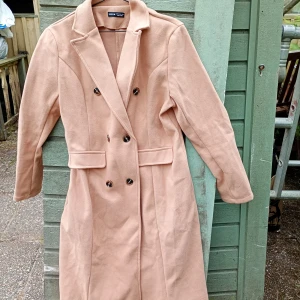 Beige kappa från SHEIN, stl XL - Snygg beige kappa från SHEIN i storlek XL. Lång modell med dubbelknäppning, klassisk krage och fickdetaljer framtill. Perfekt för dig som vill ha en stilren och trendig look under höst och vinter.