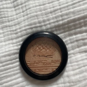 MAC  highlighter  - Supersnygg highlighter från MAC i en lyxig guldig nyans. Kommer i en rund svart dosa med genomskinligt lock och MAC-logga. Pressad puderformula med metallic finish som ger en glowig look. Perfekt för att framhäva kindben och ge extra lyster.
