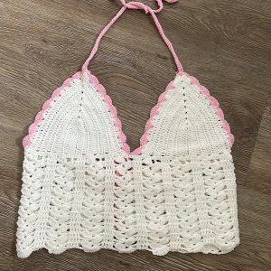 Handgjord stickad topp  - Kupa C/D, storlek S/M. Reglerbar i ryggen och nacke. Vit med rosa detaljer. 