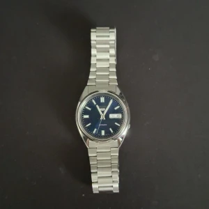 Seiko automatisk klocka med blå urtavla 37mm - Stilren Seiko automatisk klocka med blå urtavla och dag/datumvisning. Klockans skick är 9.5/10. Använd 1 gång. Box och allt följer med. Kvitto finns också
