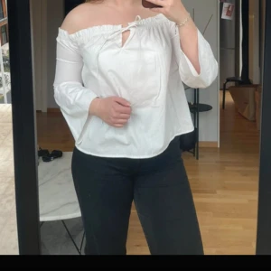 Vit offshoulder blus med knyt - Säljer en vit offshoulder blus med trekvartsärm och knyt framtill. Blusen har en lös passform och är perfekt för varmare dagar. Enkel och stilren design som passar till mycket.