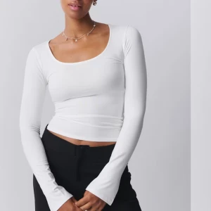 Vit långärmad topp med rundad urringning - Säljer en enkel och stilren vit långärmad topp från Monki. Toppen har en rundad, lite djupare urringning och är figurnära i modellen. Perfekt att matcha med jeans eller kjol för en clean look.