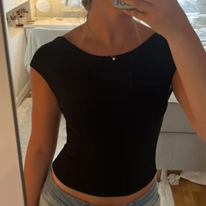 Svart topp med öppen rygg - Säljer en svart topp med korta ärmar. Toppen har en väldigt fin öppen rygg. Super skönt material. 