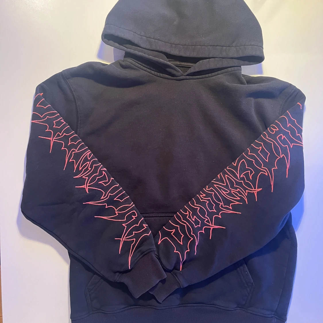 Svart hoodie med röd grafik på ärmar - 1