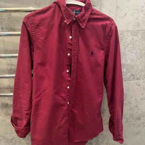 Vinröd skjorta från Ralph Lauren - Säljer en vinröd skjorta från Ralph Lauren i slim fit-modell. Skjortan är i bra skick utan några defekter. Perfekt för dig som gillar stilrena plagg med snygg passform och inför sommaren!☀️passar mer som S/M, Passar mig som är ungefär 181cm lång. Skriv privat om ni har några funderingar.